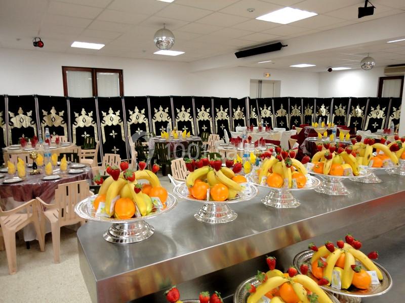 Plateaux de fruits frais disposés sur une table en métal dans une salle décorée pour un événement.