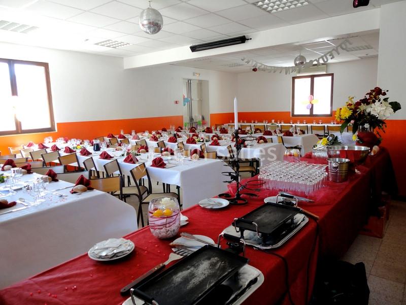 Salle de réception décorée avec des tables dressées pour un événement, buffet en premier plan.