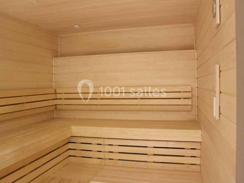 Intérieur d'un sauna en bois clair avec bancs et parois lambrissées.