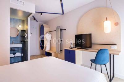 Deux équipements de fitness, un tapis de course et un vélo elliptique, dans une salle au sol en bois et murs bleus.