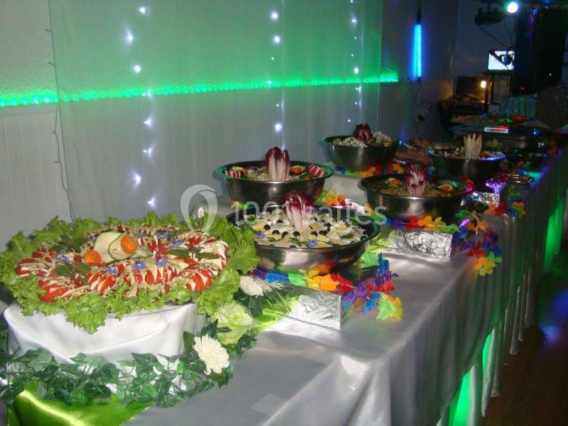 Buffet décoré avec des plats variés, disposés sur une table ornée de lumières et de feuilles colorées.