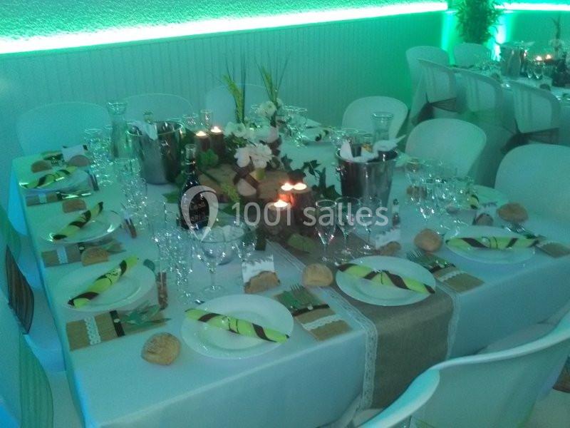 Table dressée pour un repas festif avec nappes blanches, serviettes pliées, bougies et décorations florales.