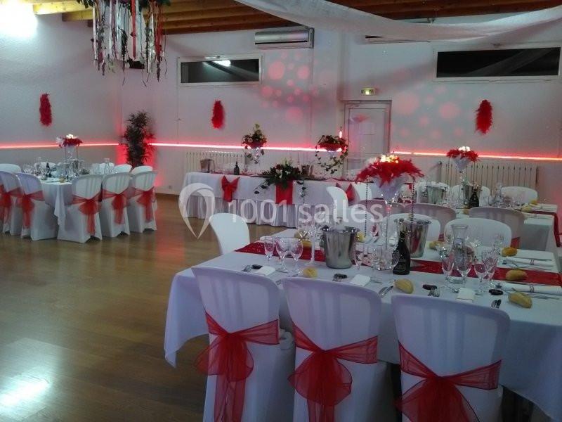 Salle de réception décorée en rouge et blanc avec tables dressées pour un événement festif.
