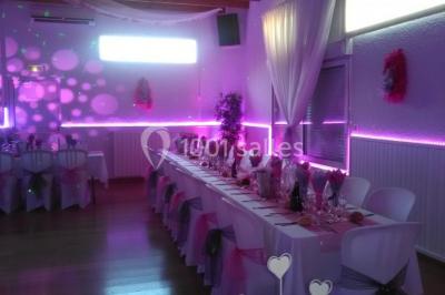 Jeu de lumières colorées dans une salle sombre avec équipement de sonorisation visible en arrière-plan.