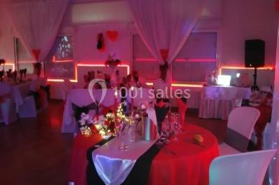 Jeu de lumières colorées dans une salle sombre avec équipement de sonorisation visible en arrière-plan.