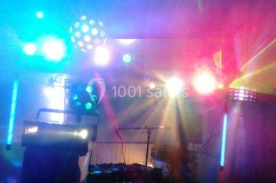 Jeu de lumières colorées dans une salle sombre avec équipement de sonorisation visible en arrière-plan.