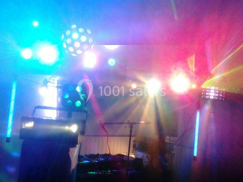 Jeu de lumières colorées dans une salle sombre avec équipement de sonorisation visible en arrière-plan.