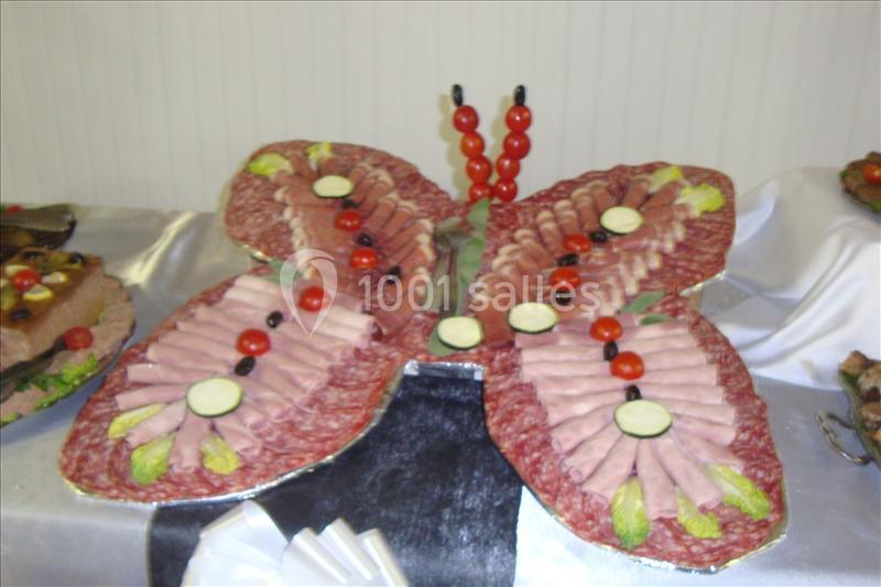 Plateau de charcuterie en forme de papillon, composé de tranches de viande, rondelles de courgette et tomates cerises.