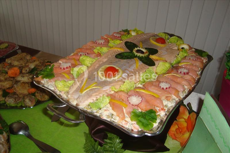 Plateau de saumon froid décoré de légumes, tranches de saumon fumé et garnitures colorées sur un lit de salade.