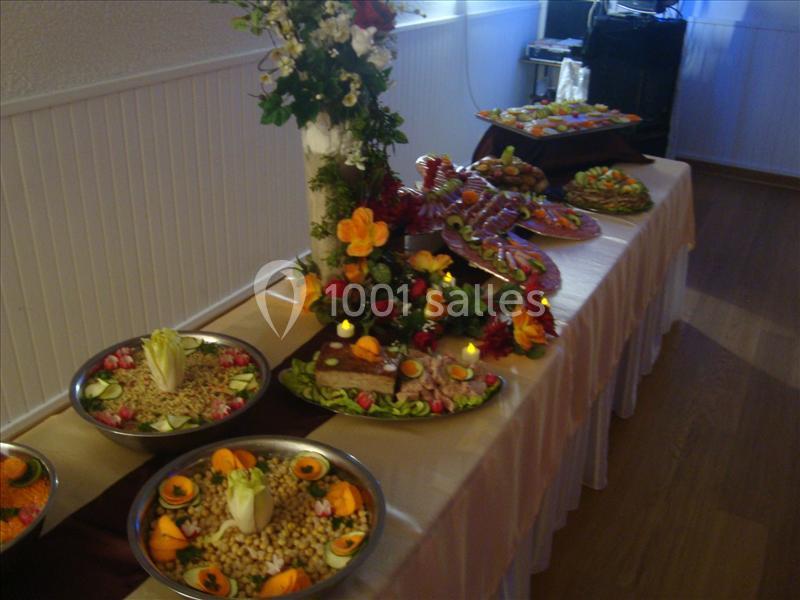 Buffet décoré avec des plats variés, incluant salades, charcuteries et garnitures, présenté sur une table ornée de fleurs.