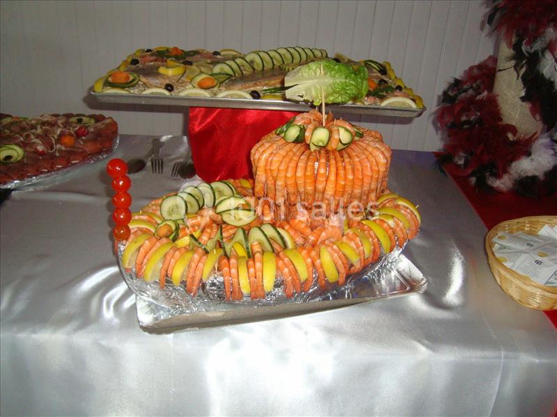Plateau de fruits de mer décoré avec des crevettes, rondelles de citron et de concombre, présenté sur une nappe blanche.