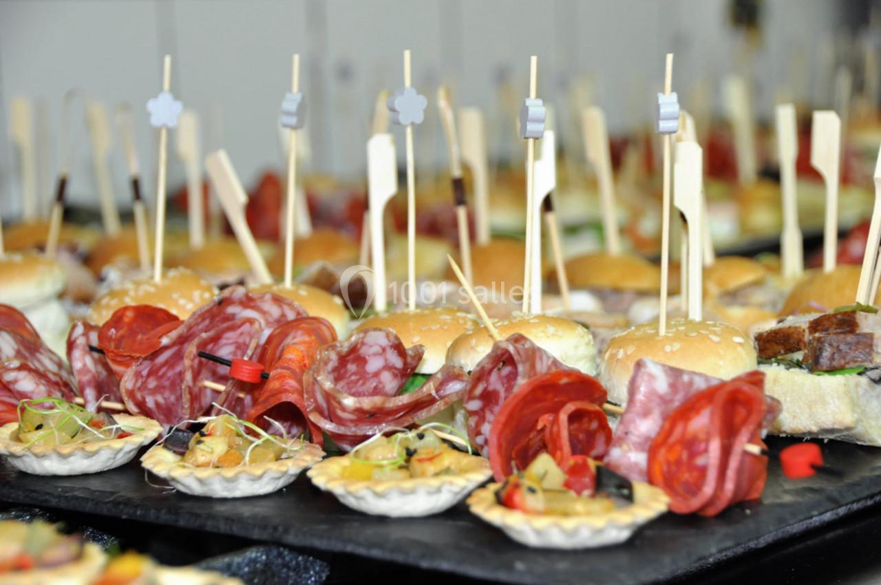 Plateau de bouchées apéritives variées comprenant mini-burgers, charcuterie et tartelettes garnies.