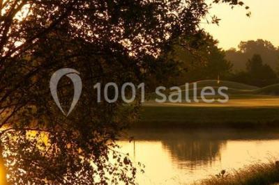 Plan d'eau entouré de pelouses et d'arbres, avec deux bouleaux au premier plan sous un ciel bleu.