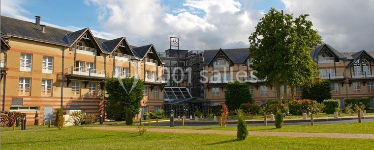 Bâtiment à plusieurs étages avec des façades en briques et toits en ardoise, entouré de pelouses et d'arbres.