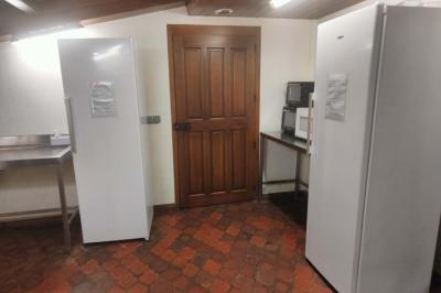 Deux réfrigérateurs blancs dans une pièce avec un sol en carrelage rouge, une porte en bois et un plan de travail.