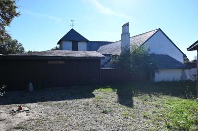 Deux réfrigérateurs blancs dans une pièce avec un sol en carrelage rouge, une porte en bois et un plan de travail.