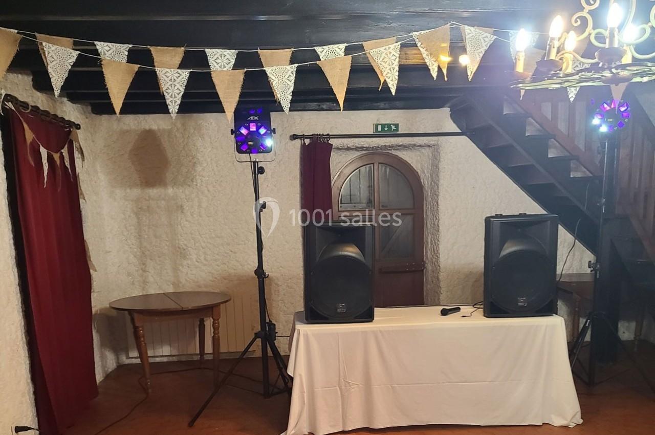 Système de sonorisation installé dans une salle rustique avec murs en pierre, guirlandes en tissu et éclairage tamisé.