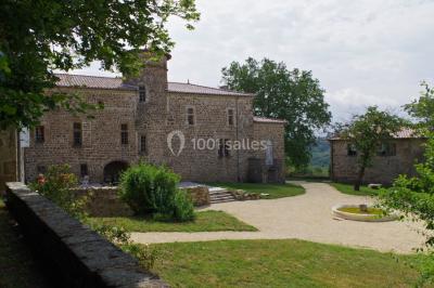 Chambre avec un lit double, draps blancs, couverture rouge, deux oreillers bleus et un mur rouge, éclairée par une fenêtre.