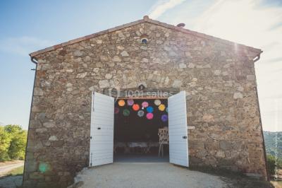 Chambre avec un lit double, draps blancs, couverture rouge, deux oreillers bleus et un mur rouge, éclairée par une fenêtre.