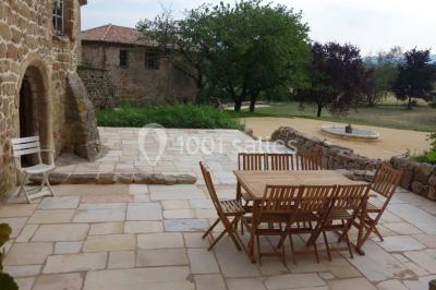 Chambre avec un lit double, draps blancs, couverture rouge, deux oreillers bleus et un mur rouge, éclairée par une fenêtre.