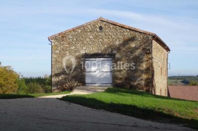 Chambre avec un lit double, draps blancs, couverture rouge, deux oreillers bleus et un mur rouge, éclairée par une fenêtre.