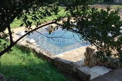 Chambre avec un lit double, draps blancs, couverture rouge, deux oreillers bleus et un mur rouge, éclairée par une fenêtre.
