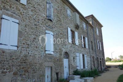 Chambre avec un lit double, draps blancs, couverture rouge, deux oreillers bleus et un mur rouge, éclairée par une fenêtre.
