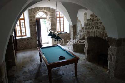 Chambre avec un lit double, draps blancs, couverture rouge, deux oreillers bleus et un mur rouge, éclairée par une fenêtre.