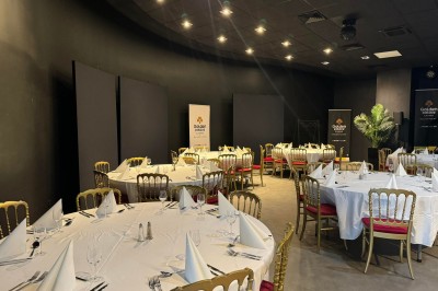 Salle de restaurant moderne avec tables en bois, chaises orange, plantes et un plafond à rayures rouges et blanches.