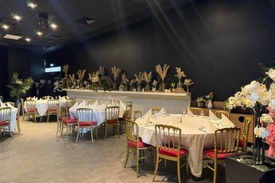 Salle de restaurant moderne avec tables en bois, chaises orange, plantes et un plafond à rayures rouges et blanches.