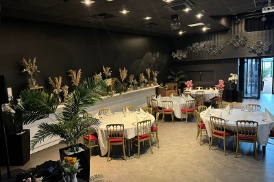 Salle de restaurant moderne avec tables en bois, chaises orange, plantes et un plafond à rayures rouges et blanches.
