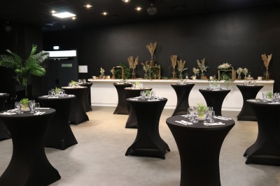 Salle de restaurant moderne avec tables en bois, chaises orange, plantes et un plafond à rayures rouges et blanches.