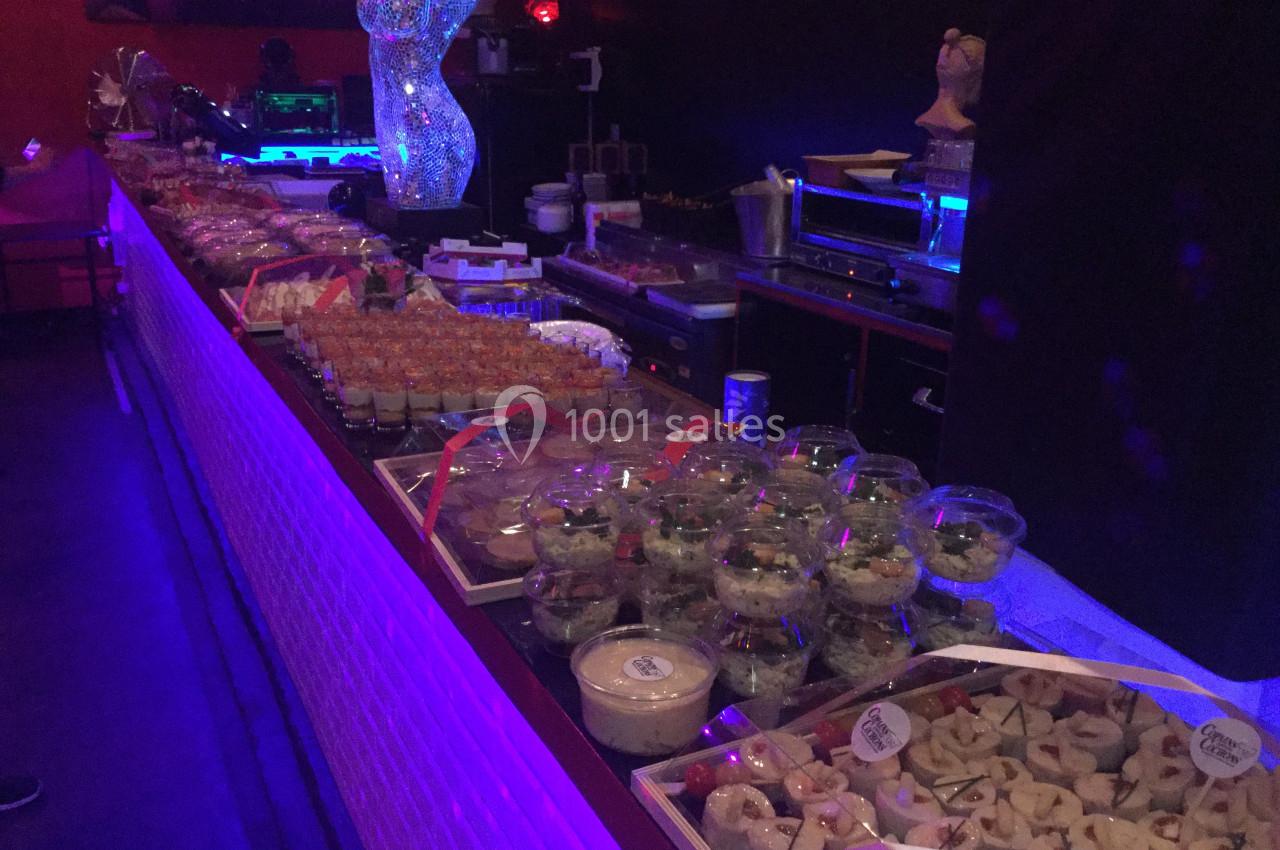 Buffet varié avec verrines, salades et amuse-bouches disposés sur une longue table dans un éclairage tamisé.