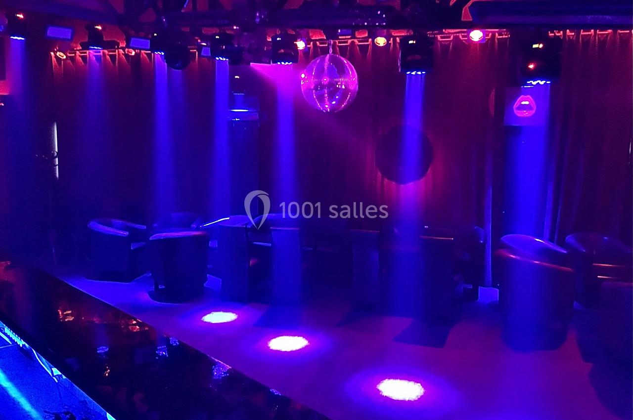 Salle de spectacle avec fauteuils, éclairage violet et bleu, et une boule à facettes suspendue au plafond.