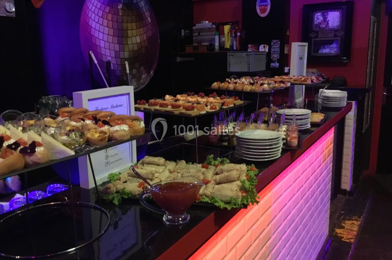 Buffet varié avec desserts, verrines, rouleaux et sauce, présenté sur un comptoir éclairé dans une ambiance festive.