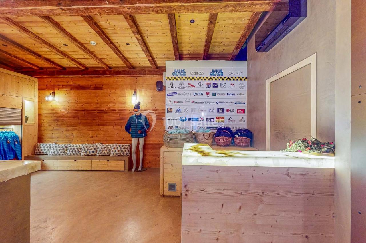 Intérieur d'un espace en bois avec un comptoir, un mannequin habillé, des étagères et un mur affichant des logos.