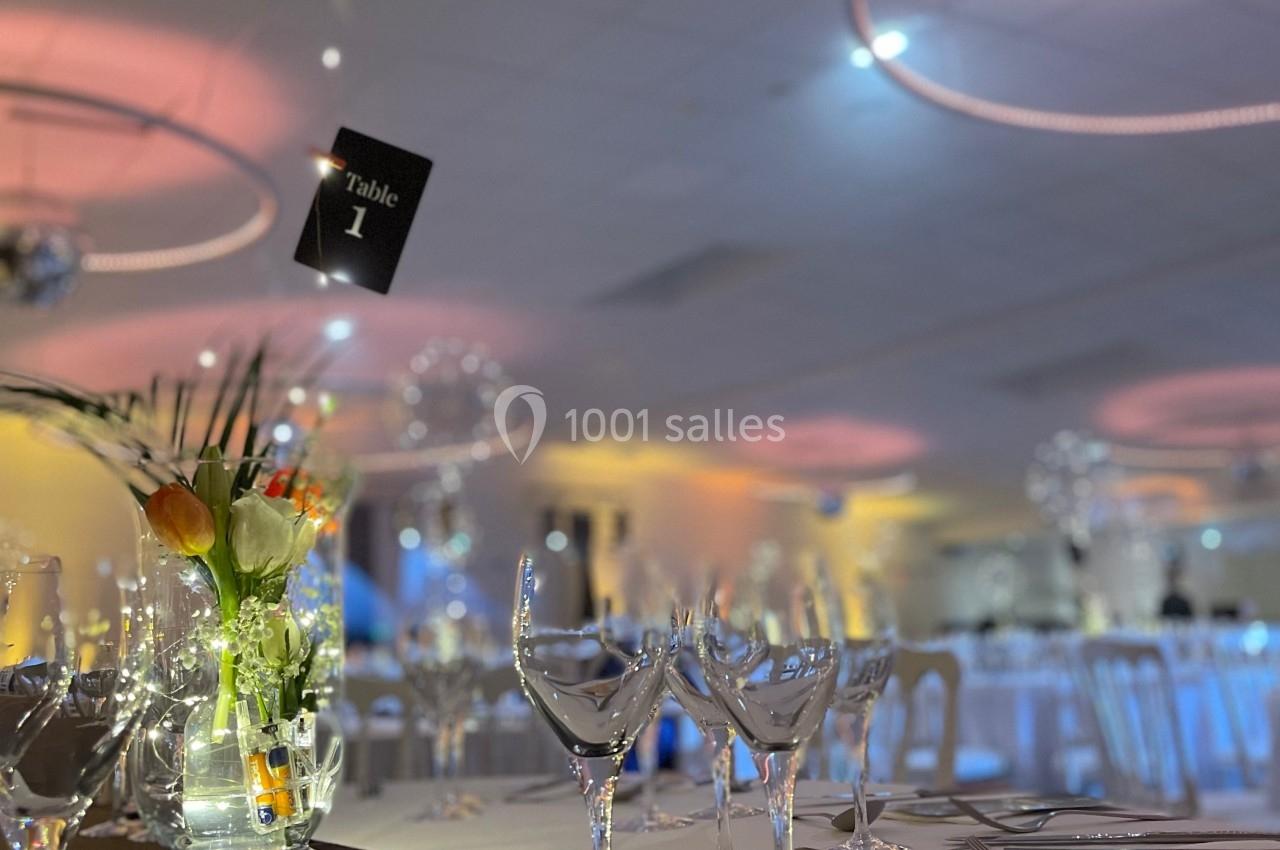 Table élégamment dressée avec des verres, des couverts, un centre de table floral et une ambiance lumineuse tamisée.