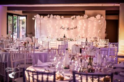 Un artiste chante sur scène avec une personne en costume étincelant sous des lumières violettes, devant un public assis.