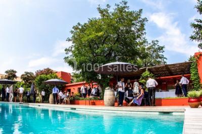 Un artiste chante sur scène avec une personne en costume étincelant sous des lumières violettes, devant un public assis.