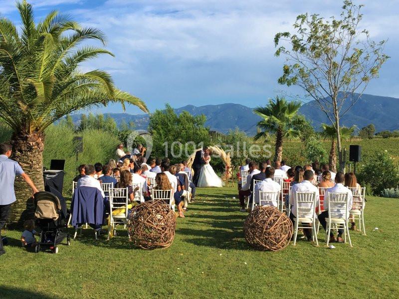 Cérémonie de mariage en plein air avec des invités assis, vue sur des montagnes et des palmiers en arrière-plan.