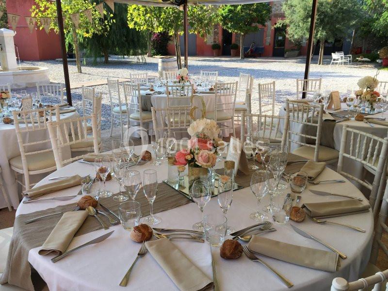 Tables élégamment dressées pour un événement en plein air, avec nappes blanches, fleurs et couverts disposés.
