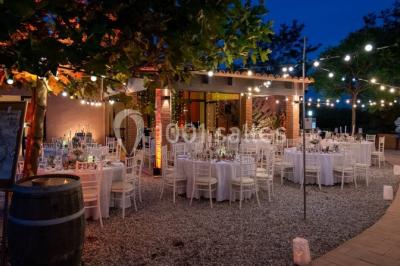 Un artiste chante sur scène avec une personne en costume étincelant sous des lumières violettes, devant un public assis.