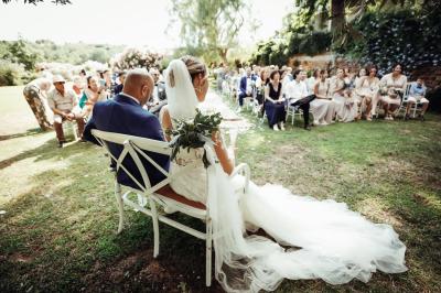 Un artiste chante sur scène avec une personne en costume étincelant sous des lumières violettes, devant un public assis.