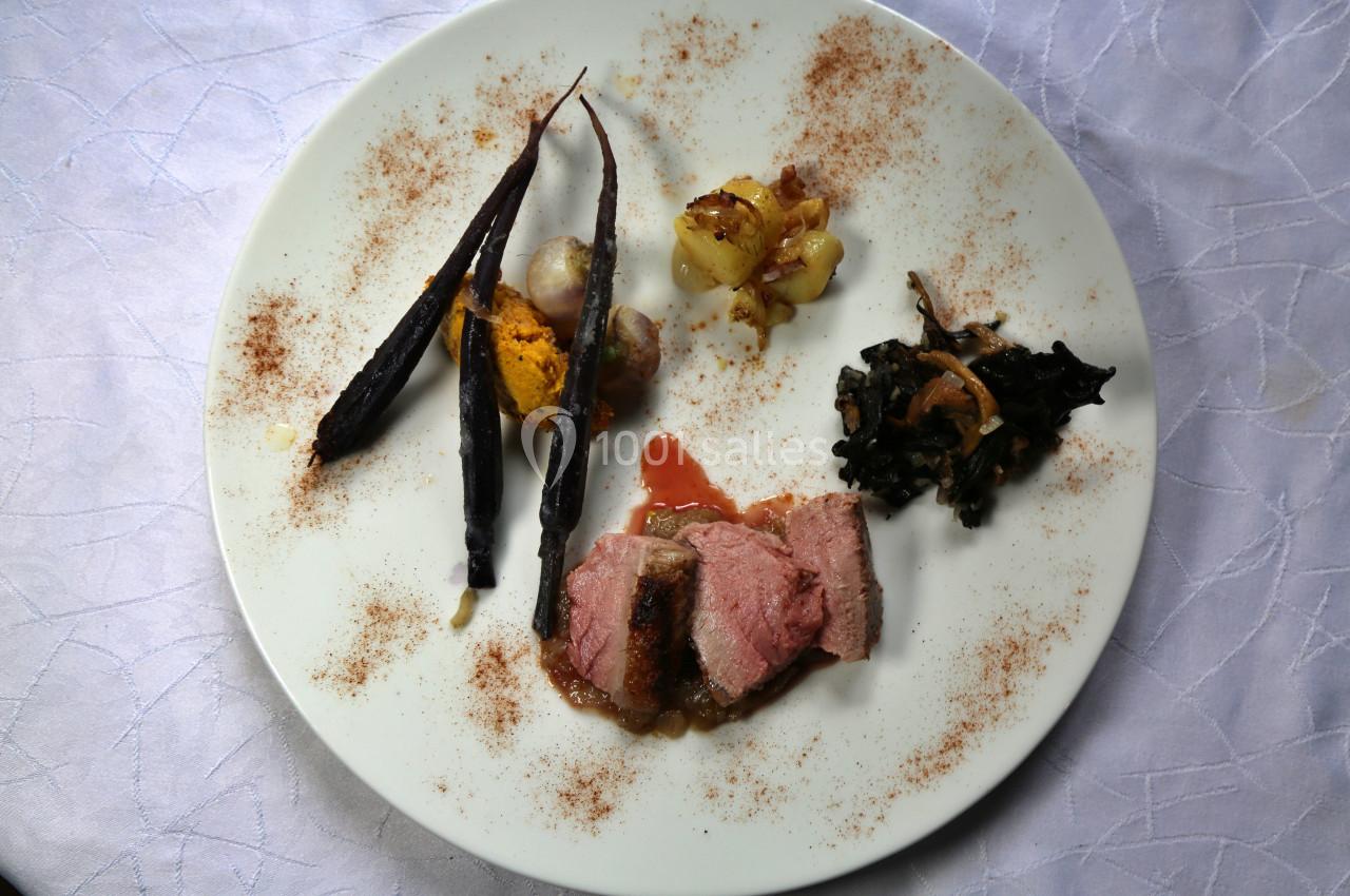 Assiette gastronomique avec viande rosée, carottes violettes, purée, légumes variés et sauce, présentée sur une nappe…