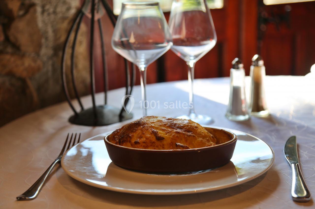 Plat gratiné dans un ramequin en céramique, servi sur une table dressée avec couverts, verres et condiments.