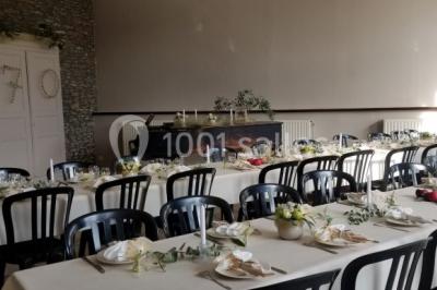 Jardin ensoleillé avec des palmiers au premier plan, pelouse verte et tables hautes recouvertes de nappes noires en arrière…