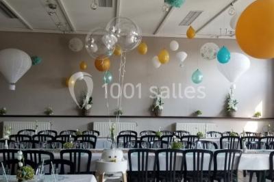 Jardin ensoleillé avec des palmiers au premier plan, pelouse verte et tables hautes recouvertes de nappes noires en arrière…