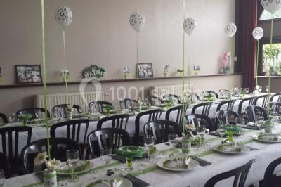 Jardin ensoleillé avec des palmiers au premier plan, pelouse verte et tables hautes recouvertes de nappes noires en arrière…