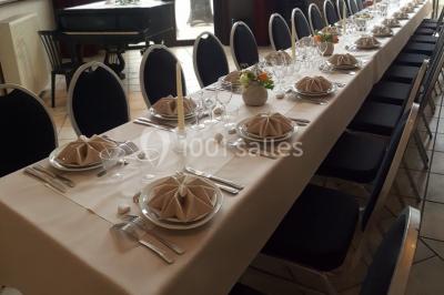 Jardin ensoleillé avec des palmiers au premier plan, pelouse verte et tables hautes recouvertes de nappes noires en arrière…