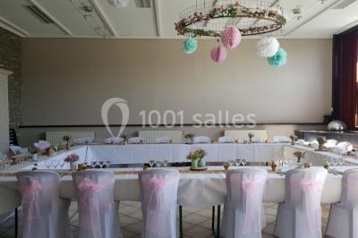 Jardin ensoleillé avec des palmiers au premier plan, pelouse verte et tables hautes recouvertes de nappes noires en arrière…